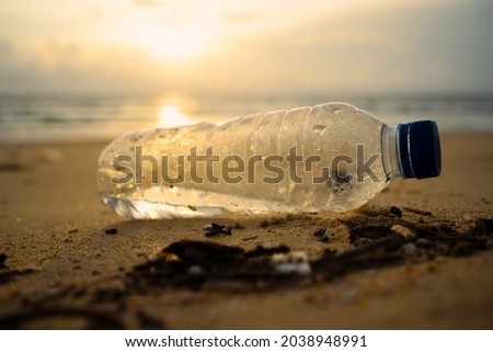 Earth day. Trash bottles dumped sandy beach during monsoon sea China. Empty used dirty plastic bottles. Plastic water bottles pollution on beach sunset. Medium Shot,Close-up,macro Royalty-Free Stock Photo #2038948991