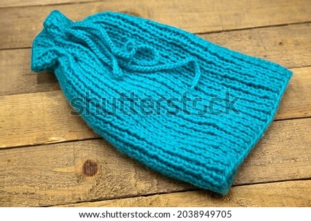 Handmade wool knitted winter blue hat isolated on wooden background
