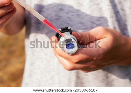 the winemaker applies a drop of grape juice with a pipette to the prism of a refractometer to determine the amount of sugar in the grape juice. High quality photo