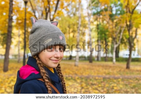 Little girl autumn park outdoor stands sideways