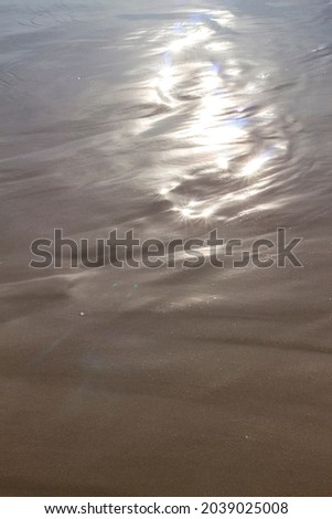 shine of the sun on the seashore on the wet sand. Holiday texture.