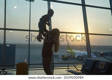 mother meet her son at the airport and pick him up in his arms
