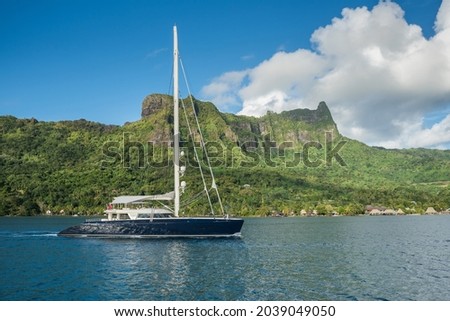Superyacht Sailing Catamaran entering Cook's Bay in, Moorea, French Polynesia. With big green mountain in the background, blue sky and sunny day. Royalty-Free Stock Photo #2039049050