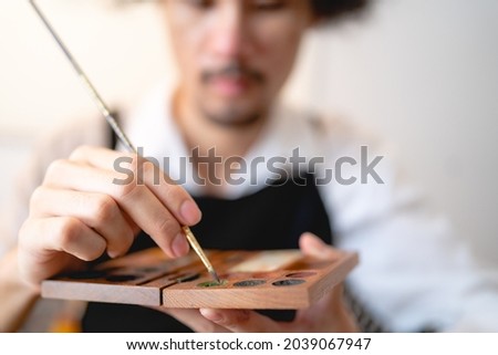 creative artist working on colours art to drawing picture with brush paint in hobby, watercolor paintbrush tool craft workshop with canvas in studio, palette easel and artwork design background