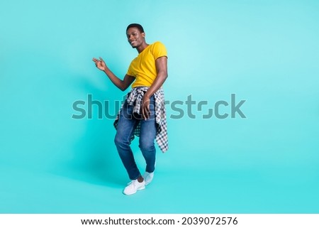 Full length photo of nice brunette hairdo millennial man dance wear yellow t-shirt jeans sneakers isolated on cyan color background