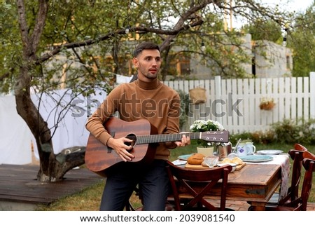 young man sits at the table and plays the guitar
