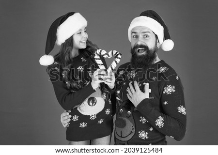Christmas time for kindness and goodness. Christmas Carol. Father and daughter with candy canes christmas decorations. Family holiday. Santa claus family look. Bearded dad and cheerful little girl