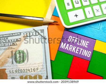 Business Concept.Text OFFLINE MARKETING writing on wooden puzzle with calculator,pencil and fake money on yellow background.