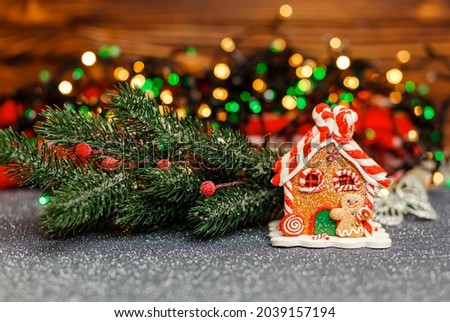 Christmas decorations with gingerbread house with beautiful bokeh lights garland closeup picture. Homemade Christmas gingerbread cookie house. Winter holidays, Happy New Year composition. Xmas dessert
