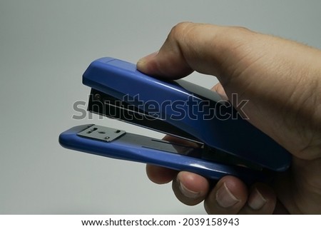 Asian man hand holding blue stapler on white background isolated Royalty-Free Stock Photo #2039158943