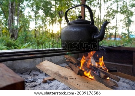 Vintage photo of water being cooked in a kettle using wood to start a fire. This photo is suitable for commercial needs around travel, camping and adventure equipment                       Royalty-Free Stock Photo #2039176586