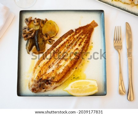 Appetizing whole fried sole fish with baked vegetables and lemon slice. Healthy seafood dinner..