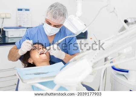 Practitioner male dentist drilling tooth to female patient in dental studio Royalty-Free Stock Photo #2039177903