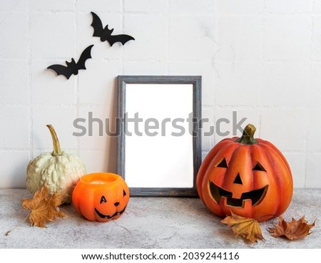 Mock up  frame with Jack o Lantern and pumpkin decor on a table. Halloween concept. Poster frame against a white wall with bats.