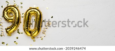 golden foil balloon number ninety. Birthday or anniversary card with the inscription 90. gray concrete background. Anniversary celebration. Banner. copy space Royalty-Free Stock Photo #2039246474