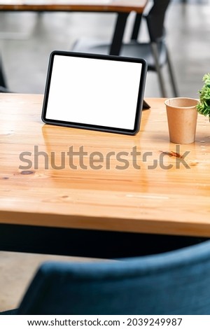 Mockup blank white screen tablet on wooden table in cafe room, vertical view.