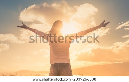 Happy joyful woman lifting her arms up to the sunny sky feeling joyful. Royalty-Free Stock Photo #2039266508