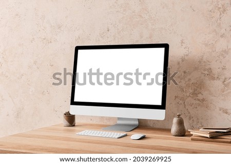 Modern computer on table near light wall