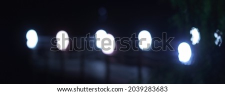 Defocused photography of street electric lamps in night city. Natural blue, white and black background.