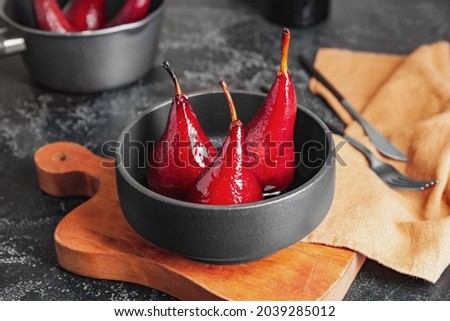Bowl with sweet poached pears in red wine on dark background