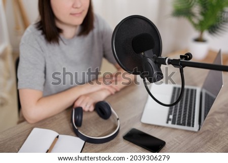 journalism, podcast and blogging concept - young woman in sound recording studio with laptop, microphone and headphones