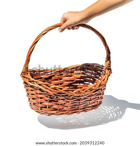 Hand holding wicker basket isolated on white.