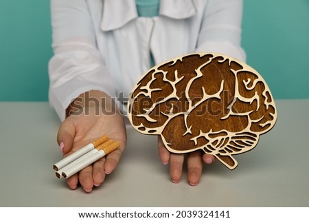 Wooden model of brain and cigarette in the hands of a doctor. Smoking addiction