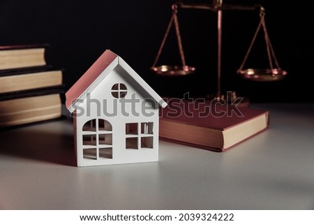 Sale of real property concept. Wooden model of house and law book at notary office