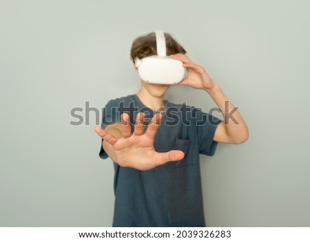 Teenager boy playing virtual reality over grey background, digital technology concept, innovative technologies