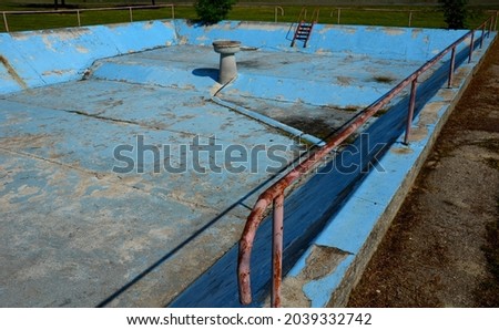 an old empty concrete pool on each square. It has railings and steps made of metal. Water is used by firefighters against fire. It is not hygienically clean for bathing and swimming