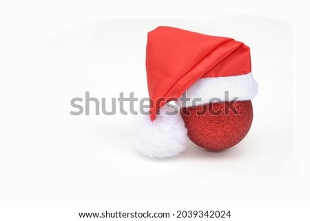 Red Christmas ball with Santa hat on a white background. Space for your text. Minimal creativity and style. Christmas card concept.