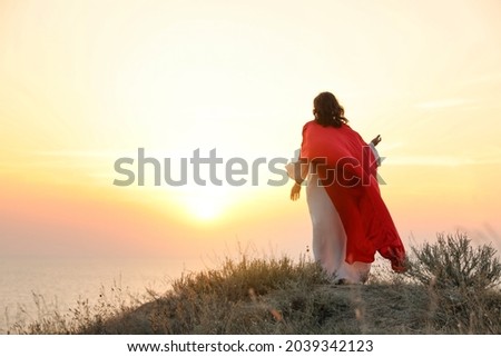 Jesus Christ on hills at sunset, back view. Space for text Royalty-Free Stock Photo #2039342123