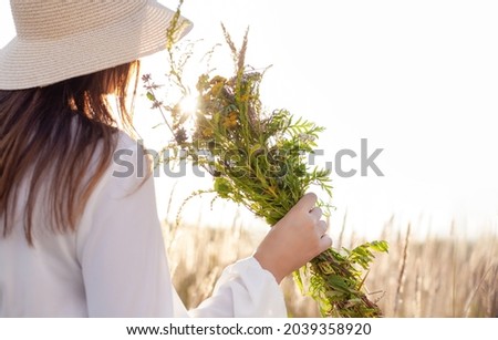 Summer lifestyle portrait of a woman holding a bouquet of field flowers, herbs. She is standing on a field of grass.Happiness and love concept. Copy space Royalty-Free Stock Photo #2039358920
