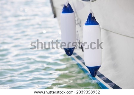 Two white fenders suspended between a boat and dockside for protection. Maritime fenders Royalty-Free Stock Photo #2039358932