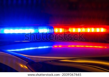 Detail of police car with lights flashing with red and blue colors on blurred background of city street