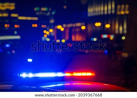 Detail of police car with lights flashing with red and blue colors on blurred background of city street