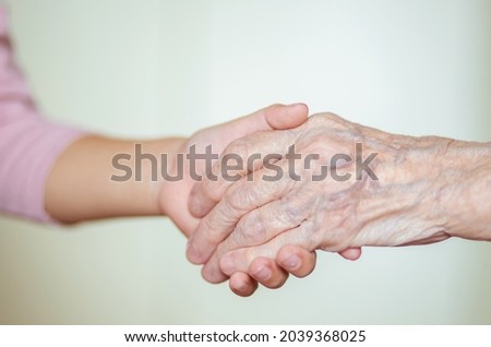 The hands of the child in the hands of the grandmother, the old brownish skin in the elderly woman, motherly love and care.
