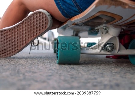 Photograph of a cruise board from below, turquoise wheels and a sneaker sole.