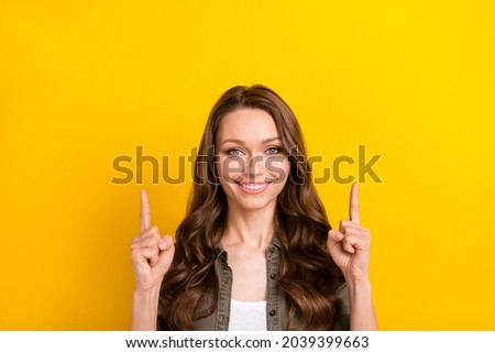 Photo of pretty sweet young lady wear green shirt looking pointing up fingers empty space isolated yellow color background