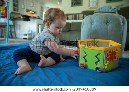 Baby boy sitting down playing with toy.
