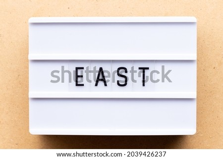Lightbox with word east on wood background