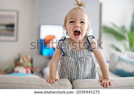 A cute little girl watching tv at home