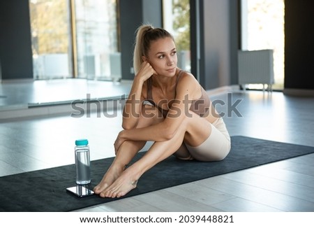 Relax time, break. Portrait of young sportive happy girl, coach in sportswear doing yoga on mat at meditation center, indoors. Concept of healthy lifestyle, wellbeing, mental health, harmony, beauty