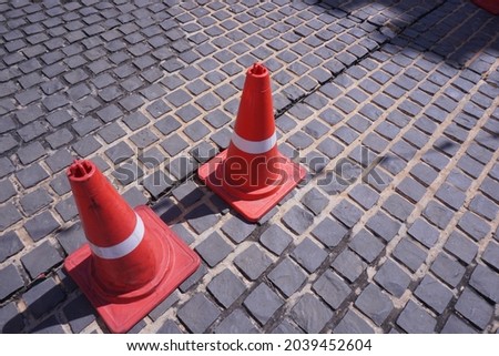 Close-up of traffic cone with white and red stripes on the gray concrete road. Vintage background with copy space in Thailand. 