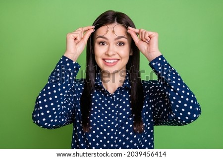Photo of hooray brunette hairdo young lady hold spectacles wear blue shirt isolated on green color background