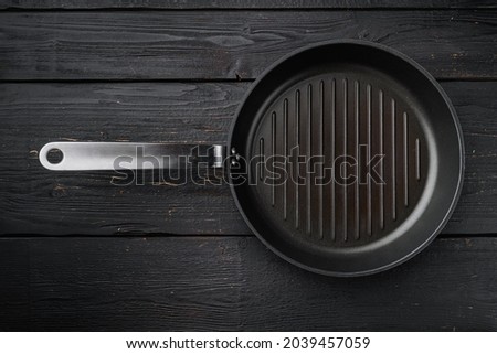 Cast iron grill pan set with copy space for text or food with copy space for text or food, top view flat lay, on black wooden table background