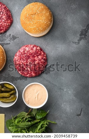 Homemade hamburger. Raw beef patties, sesame buns with other ingredients set, on gray stone background, top view flat lay, with copy space for text