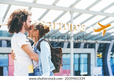 Happy interracial couple meeting at the airport. Husband kissing wife and embracing her at departure gates, saying goodbye before her business trip
