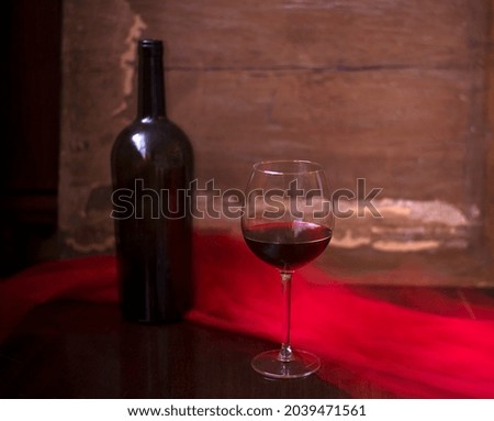 a glass of red wine on the background of a bottle with a red scarf
