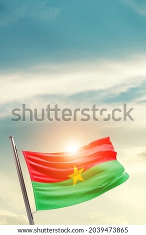 Burkina Faso national flag waving in beautiful clouds.
